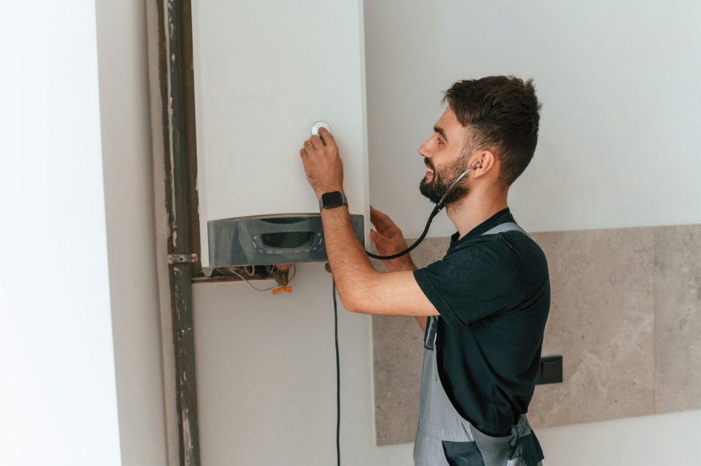 A man repairs a boiler. Listens to it using a stethoscope